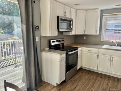 Kitchen with appliances with stainless steel finishes, dark wood-style flooring, white cabinets, and light countertops