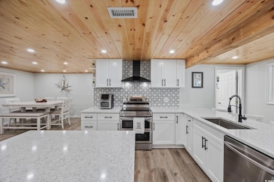 Kitchen featuring white cabinets, light stone counters, decorative backsplash, light wood-style flooring, and recessed lighting