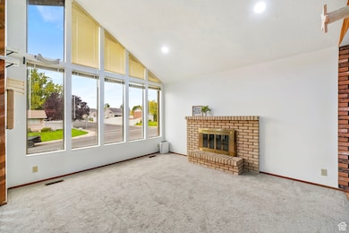 Unfurnished living room with a brick fireplace, carpet floors, and high vaulted ceiling