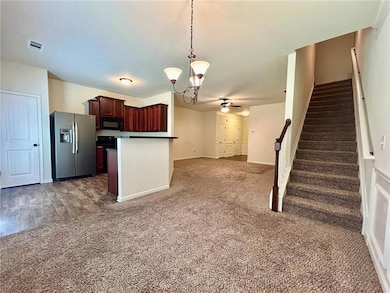 Kitchen featuring stainless steel fridge, black microwave, a chandelier, and carpet