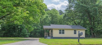View of front facade featuring crawl space, a shingled roof, a forest view, and asphalt driveway
