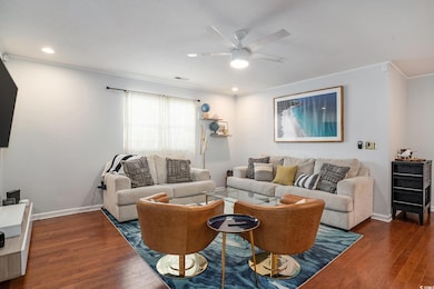 Living area with wood finished floors, visible vents, crown molding, ceiling fan, and baseboards