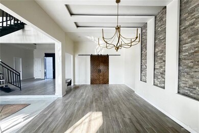 Unfurnished dining area featuring wood-type flooring, a barn door, and an inviting chandelier