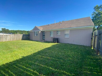 Rear view of house featuring central AC and a lawn