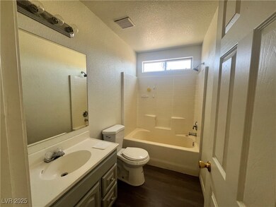 Full bath with wood finished floors, a textured wa