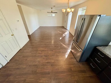 Kitchen featuring freestanding refrigerator, dark wood-style floors, pendant lighting, open floor plan, and a chandelier