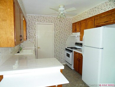 The kitchen has tiled counter top, gas oven and ra