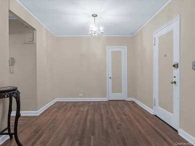 Entry way and foyer area featuring crown molding, with wood finished floors and a walk in closet