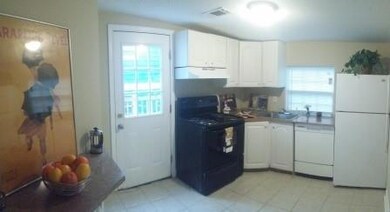Kitchen featuring white appliances, under cabinet range hood, plenty of natural light, and white cabinets