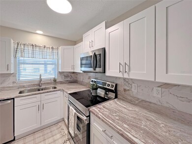 Beautifully updated Kitchen featuring white shaker, wood cabinets, granite countertop, stainless steel appliances and custom tiled backsplash.