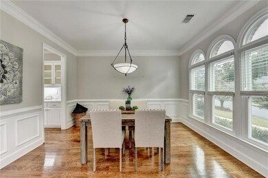 Dining room with ornamental molding, light wood-type flooring, wainscoting, and a decorative wall