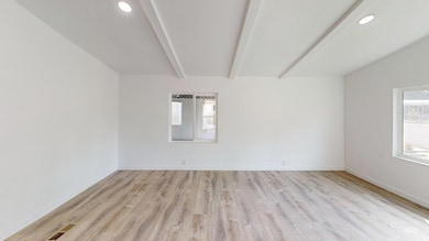 Empty room with beamed ceiling, recessed lighting, and light wood-style flooring