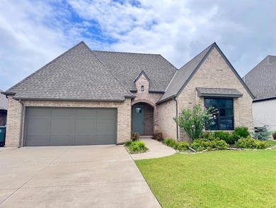 French country inspired facade featuring roof with shingles, brick siding, and concrete driveway