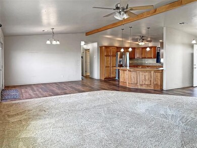 Kitchen with ceiling fan, brown cabinets, open floor plan, and dark wood-type flooring