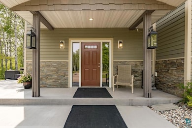 Entrance to property featuring stone siding and a porch