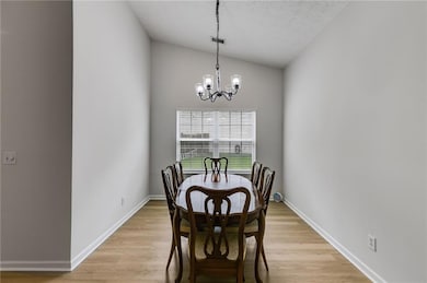 Dining room with vaulted ceiling, a chandelier, light wood-style floors