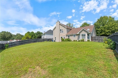Back of house featuring a fenced backyard, a garage, and a chimney