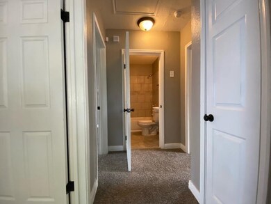 Hall featuring dark colored carpet and baseboards