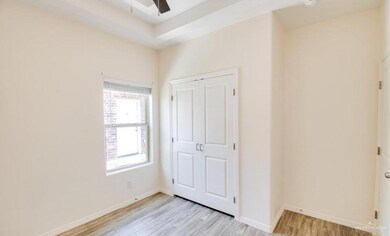Unfurnished bedroom with a raised ceiling, ceiling fan, light wood-type flooring, and a closet