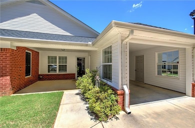 Entrance to property featuring brick siding, a shingled roof, and concrete driveway