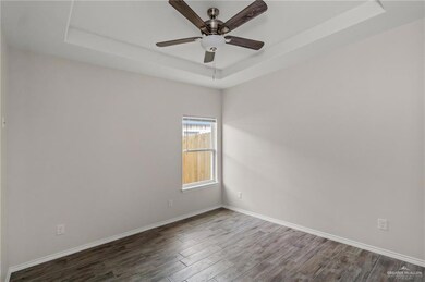Spare room with a raised ceiling, dark hardwood / wood-style flooring, and ceiling fan
