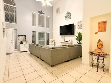 Living area featuring light tile patterned floors, a towering ceiling, and a ceiling fan