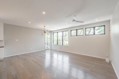 Empty room featuring hardwood / wood-style floors, ceiling fan with notable chandelier, and a healthy amount of sunlight