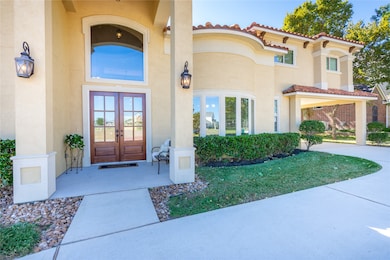 The front walkway leads to an impressive double-door entrance accented by stately columns, charming sconces, and lush greenery. This entry sets the tone for the elegance found throughout the home.