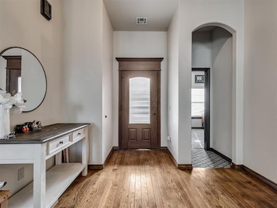 Entrance foyer with baseboards, visible vents, arc