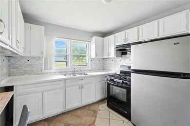 Kitchen with freestanding refrigerator, gas stove, under cabinet range hood, and white cabinets