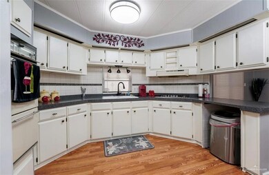 Kitchen with white cabinetry, tasteful backsplash, light hardwood / wood-style floors, and sink