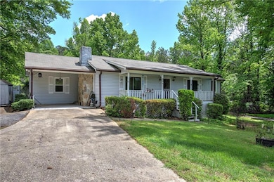 Ranch-style home featuring asphalt driveway, cover