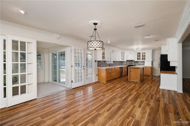 Kitchen with tasteful backsplash, stainless steel dishwasher, sink, decorative light fixtures, and a center island