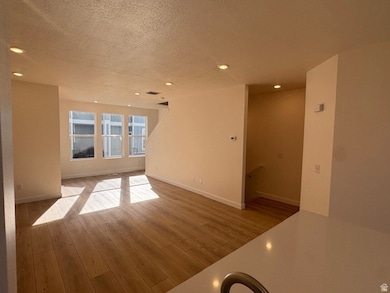 Unfurnished living room with light wood finished floors, a textured ceiling, and recessed lighting