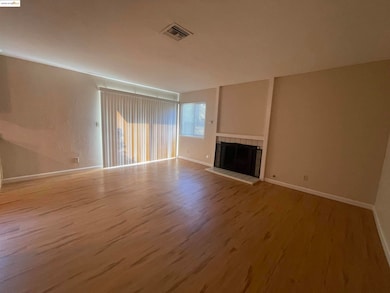 Unfurnished living room featuring a fireplace, light wood-style flooring, and a textured wall