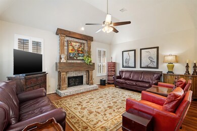 The family room features raised ceilings, hardwood floors and custom updated gas log fireplace with brick surround and wood mantle.