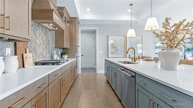 NOT ACTUAL PROPERTY - Kitchen with light countertops, a sink, a raised ceiling, custom exhaust hood, and stainless steel appliances