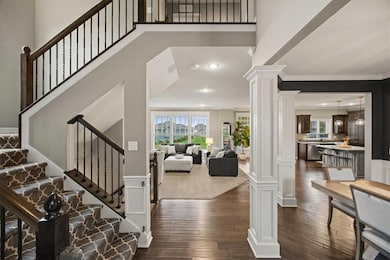 Foyer featuring ornate columns, dark wood-style floors, recessed lighting, stairs, and crown molding