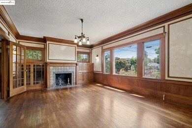 Unfurnished living room featuring crown molding, a textured ceiling, wood finished floors, a chandelier, and a tile fireplace