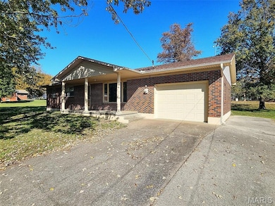 Ranch-style home featuring a porch, brick siding, an attached garage, and driveway