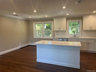 Kitchen featuring recessed lighting, white cabinetry, crown molding, backsplash, and light stone countertops
