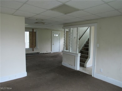 Carpeted empty room featuring stairway and a paneled ceiling