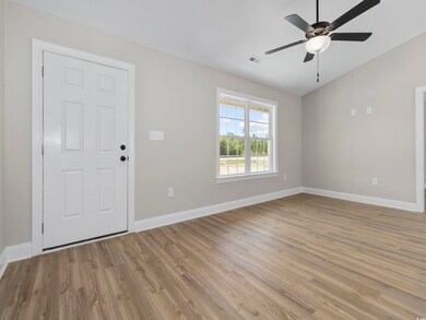 Interior space featuring baseboards, a ceiling fan, visible vents, lofted ceiling, and light wood finished floors
