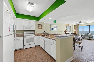 Kitchen featuring white appliances, a sink, a textured ceiling, open floor plan, and a peninsula