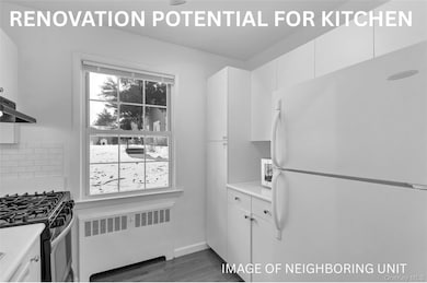 Kitchen featuring freestanding refrigerator, radiator, stainless steel gas stove, white cabinets, and dark wood-type flooring