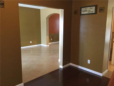 Tiled empty room featuring arched walkways and bas