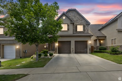 View of front of property featuring stone siding, a garage, driveway, a front yard, and stucco siding