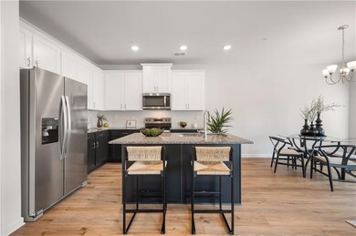Kitchen featuring appliances with stainless steel finishes, dark cabinets, white cabinetry, recessed lighting, and light stone counters