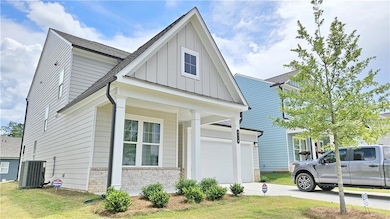 View of front of house featuring board and batten siding, driveway, brick siding, a front lawn, and an attached garage