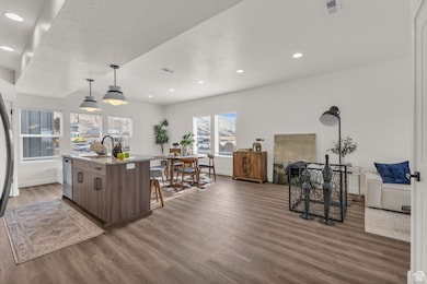 Kitchen featuring wood finished floors, a sink, baseboards, a center island with sink, and a breakfast bar area